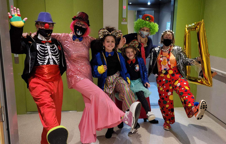 3 cliniclowns et 2 clinijuniors déguisés en clowns réalisant un pas de danse en levant la jambe