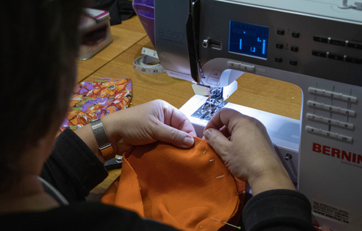 Een vrijwilliger van Clinicoeurs die aan het naaien is met een naaimachine