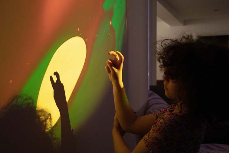 Les mains d'une fille formant des signes sur les murs avec des couleurs allant du vert au jaune.