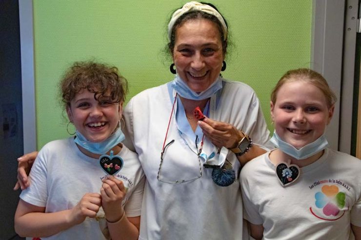 Deux enfants avec des t-short de l'asbl accompagné d'une femme avec une blouse blanche